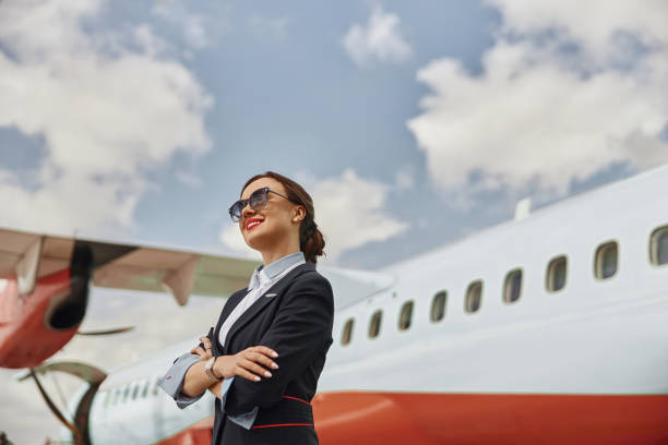 istock Smiling stewardess on runway near airplane jet 1329895368