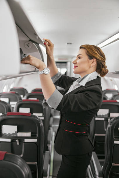 istock Stewardess take baggage from shelf in airplane 1329896991