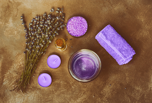 High angle shot of lavender bouquet and lavender spa products on a brown painted background