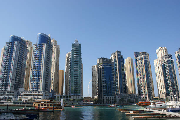 iates no pano de fundo de arranha-céus em um distrito de dubai (marina). arranha-céus refletindo em água azul - dubai skyscraper architecture united arab emirates - fotografias e filmes do acervo