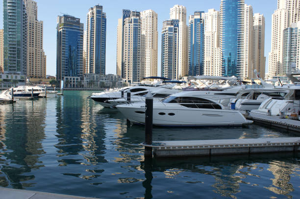 iates no pano de fundo de arranha-céus em um distrito de dubai (marina). arranha-céus refletindo em água azul - dubai skyscraper architecture united arab emirates - fotografias e filmes do acervo