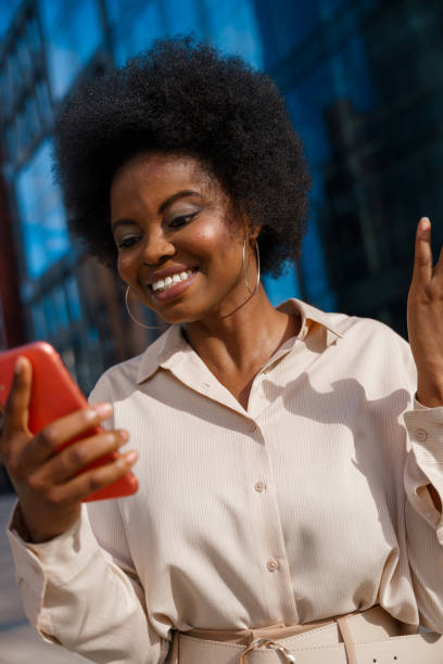 istock A young dark skinned office worker is smiling waving someone in a video chat on her red smartphone 1329908412