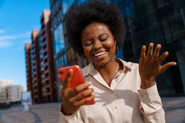 istock A young dark skinned office worker is talking to someone in a video chat on her red smartphone with a smile 1329908413