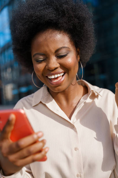 istock A young dark skinned office worker is laughing at  jokes, she read  on her red smartphone, 1329908416