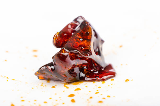 a piece of dark amber cannabis wax concentrate close up on white paper stock photo