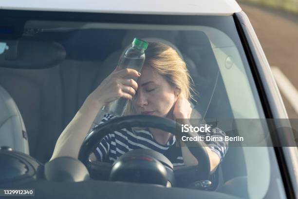 Exhausted Girl Driver Suffering From Headache Heat Hot Weather Applies Bottle Of Water To Forehead Stock Photo - Download Image Now