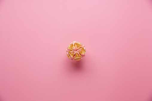 MulticolorÂ handmade modularÂ origami ball or Kusudama Isolated on pink background. Visual art, geometry, art of paper folding, paper crafts. Top view, close up, selective focus, copy space.
