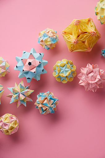 Set of multicolorÂ handmade modularÂ origami balls or Kusudama Isolated on pink background. Visual art, geometry, art of paper folding, paper crafts. Top view, close up, selective focus, copy space.