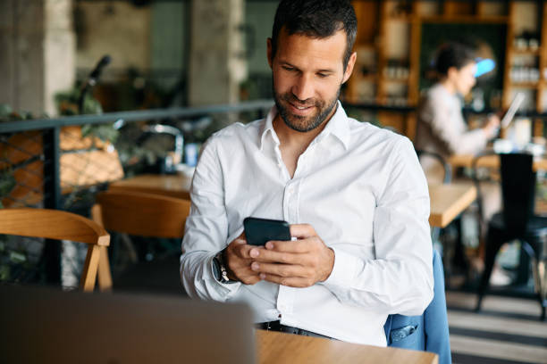 istock Happy businessman text messaging on mobile phone in a cafe. 1329913163