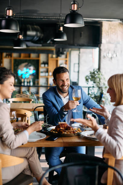 glücklicher geschäftsmann, der wein trinkt, während er mit kollegen im restaurant zu mittag geht. - restaurant chef gourmet dining stock-fotos und bilder