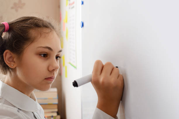 istock Little girl writing something on board while conducting the home assignment 1329915384