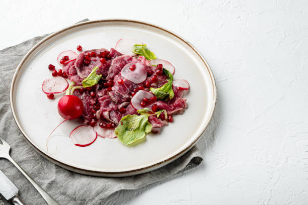 wołowina carpaccio zimna przekąska, z rzodkiewką i granatem, na talerzu, na białym kamiennym tle, z kopią miejsca na tekst - beef carpaccio zdjęcia i obrazy z banku zdjęć