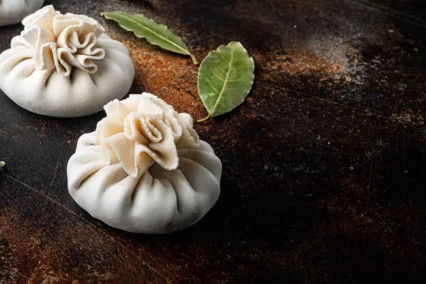 Photo of Manti or manty dumplings, popular asian dish, on old dark rustic background, with copy space for text