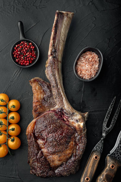 istock Barbecue dry aged Tomahawk Steak beef meat, on black stone background, top view flat lay 1329918650