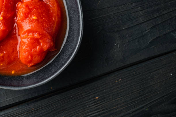 istock Peeled tomatoes, on black wooden table background, top view flat lay  with copy space for text 1329921817