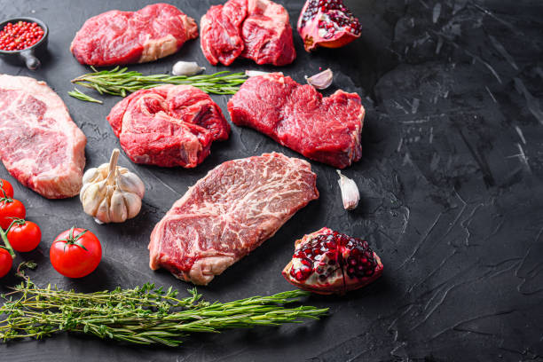 istock Alternative raw beef steak cuts with top blade, chuck roll and rump steak, with herbs and pomegranate side view, space for text. 1329922904