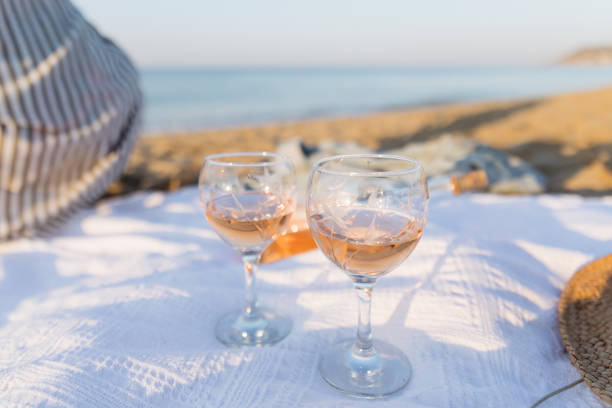 Summer picnic on the beach at sunset. Young woman with glass of rose wine. Weekend picnic. Close up. stock photo