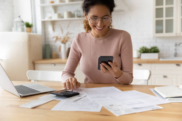 jovem sorridente satisfeita com o serviço móvel de pagamento online. - check writing currency finance - fotografias e filmes do acervo