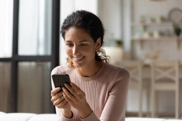 istock Smiling millennial hispanic woman using smartphone at home. 1329930125