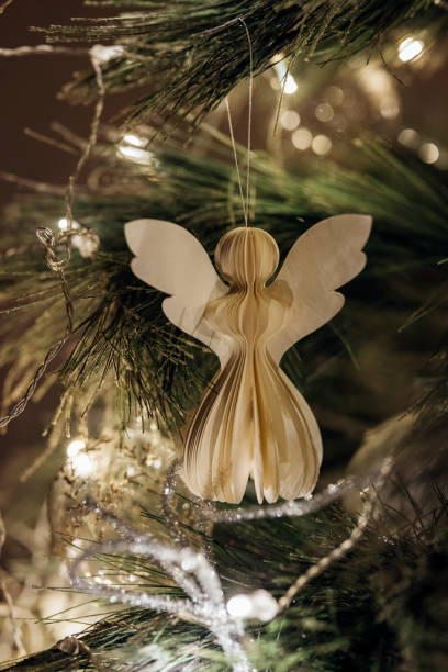 A close up shot of a white angel bauble on a glowing Christmas tree