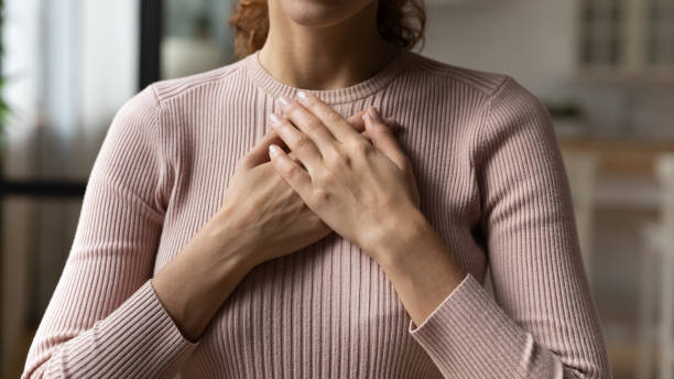 istock Young woman holding folded hands on chest heart. 1329931131