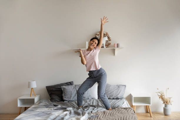 istock Happy young hispanic woman dancing on bed. 1329931141
