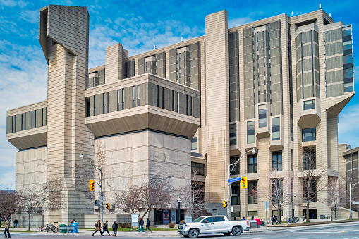 People and car move beside Robarts Library, the main library on the University of Toronto campus, in downtown Toronto Ontario Canada on a sunny day.