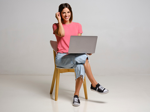 A studio portrait of a happy woman against a grey background.