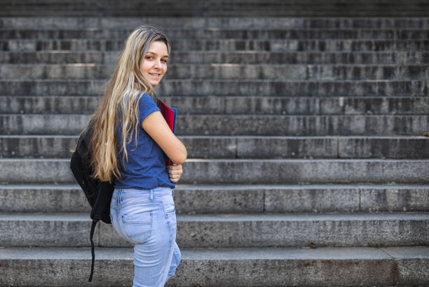 istock Student girl holding books while walking in school. Back to school concept 1329931972