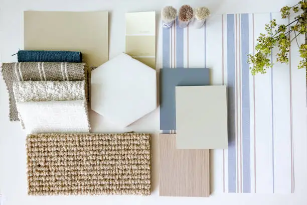 Texture and material samples for interior design projects, such as rugs, wallpaper, fabric and tiles, laid out to illustrate a modern soft blue beach house styling scheme