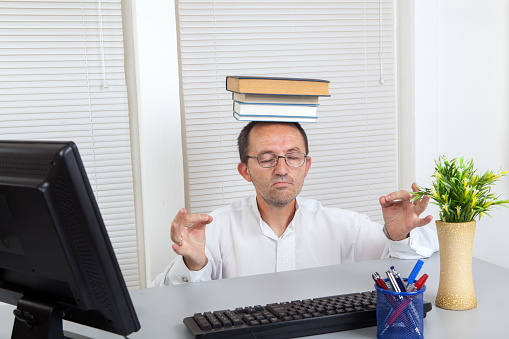 Senior businessman in office with books meditating