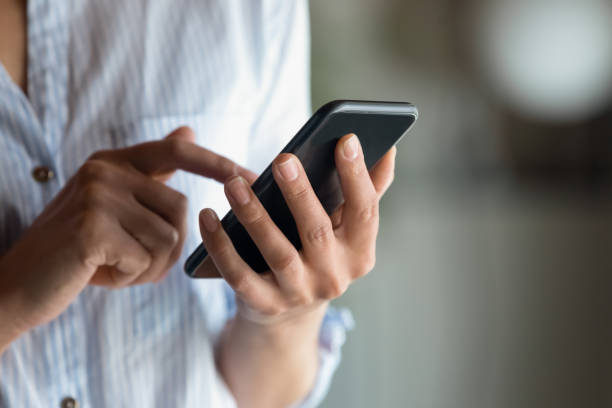 close up woman holding smartphone in hand, typing on screen - calling imagens e fotografias de stock