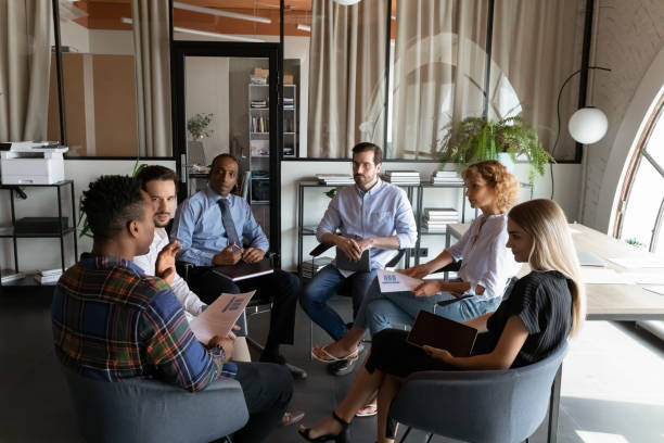 istock Serious diverse businesspeople discussing project statistics, sitting in circle 1329936163