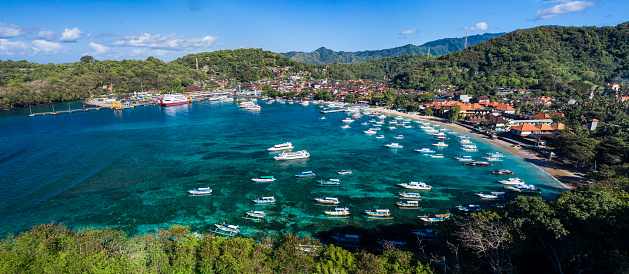 Aerial drone panorama taken by drone of the peaceful village of Padangbai located on the Eastern shore of Bali with the harbour being the main departure access to Lombok in Indonesia.