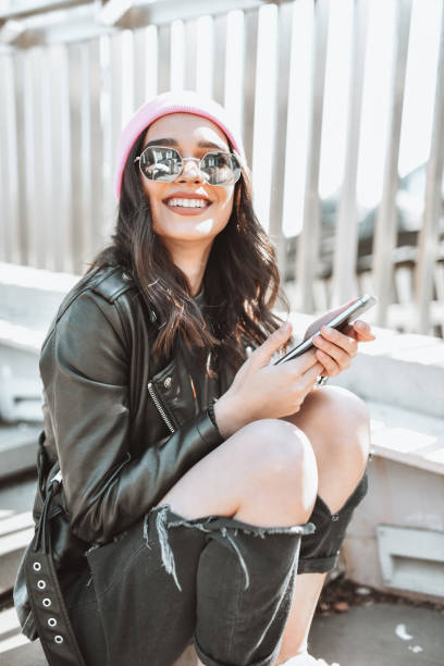 bella femmina che usa il telefono mentre si rilassa sulle scale all'esterno - rock staircases foto e immagini stock