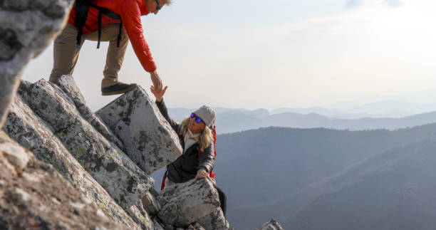 istock Mature couple climb up sunny mountain ridge 1329942801