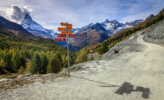 Gravel road and a sign in the mountains near Zermatt with Matterhorn in the background