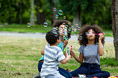 istock Happy African-American Family is Having a Picnic in a Park and Blowing a Bubbles. 1329947607