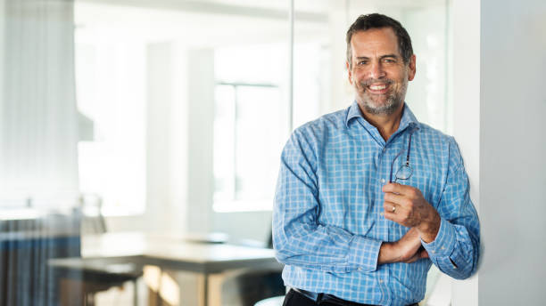istock Smiling mature business man standing alone in a bright modern office 1329949207