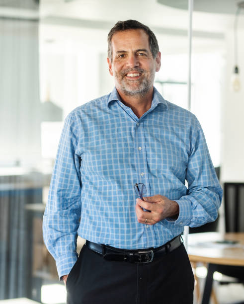 istock Mature business man smiling while standing in a bright modern office 1329949217