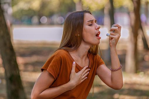 A Woman with Breathing Problems is Using an Asthma Inhaler Due to the Problems With Respiratory System.