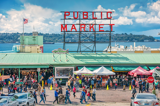 People walk at the Pike Place Market in Seattle Washington USA on a sunny day.