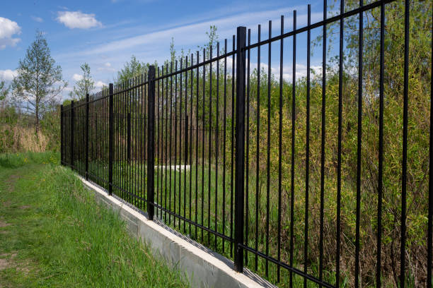 Metal fence on a cement foundation against the blue sky. Diagonal arrangement Long black transparent metal fence with concrete foundation against blue sky. Diagonal arrangement. aluminium stock pictures, royalty-free photos & images