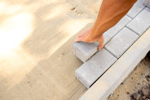 istock Bricklayer's hand lays paving slabs in prepared sand mixture. Process of laying sidewalk, landscaping garden 1329961246