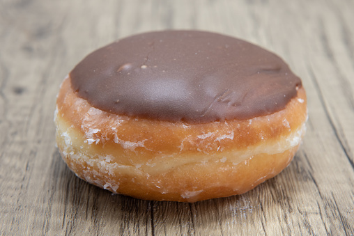 Custard raised donut is textured with chocolate coating for a sweet treat delight.