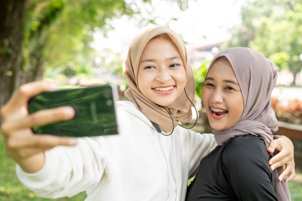 istock muslim friend taking selfie or video calling outdoor using her smart phone during sport break outdoor 1329962425