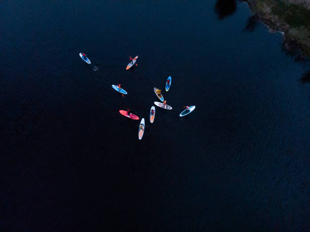 Tourists floating on SUP Board in blue sea. Top view of group of people on SUP-Boards floating in quiet clear sea stock photo