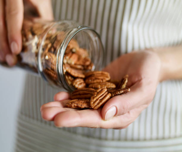 Holding pecans Close up shot of a woman taking pecans from a glass jar palm fiber stock pictures, royalty-free photos & images
