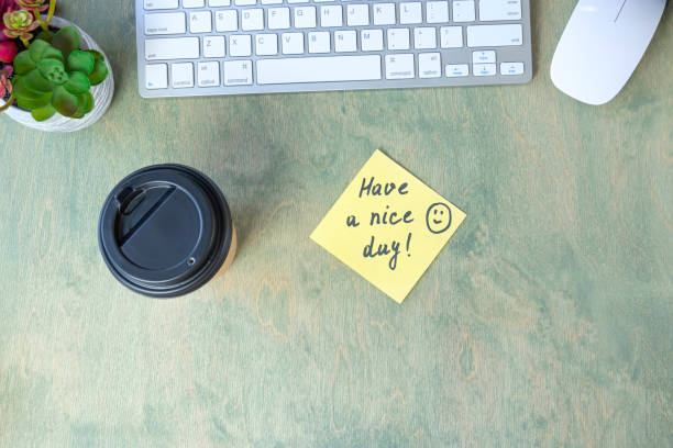 istock note with words HAVE A NICE DAY with smile and coffee in papper cup, keyboard, cactus and mause on a wooden table. concept of good start to day. top view of the desktop 1329979838