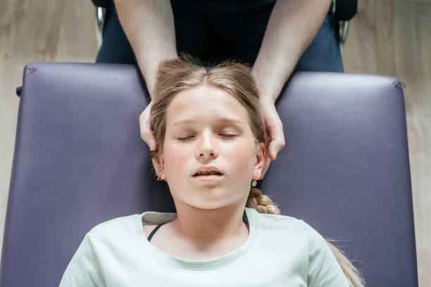 leczenie ostheopatyczne dziewczynki za pomocą cst delikatnej techniki hands-on, napięcie ośrodkowego układu nerwowego łagodzi - head massage headache massaging alternative therapy zdjęcia i obrazy z banku zdjęć